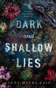 Von seichten Lügen und dunklen Geheimnissen (Dark and Shallow Lies) - Ginny Myers Sain © Panini Verlag, dunkel blauer Hintergrund, am Rand Blumen, oben rechts ein Alligator
