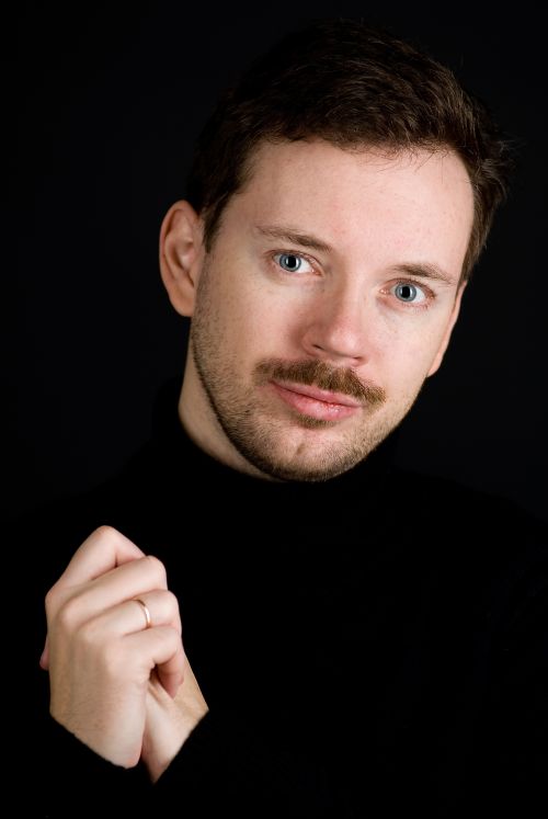 Alexey Pehov © Evgenyi Garzevich/ Piper-Verlag, Portrait vor schwarzem Hintergrund, Autor trägt schwarzen Pullover, sodass Gesicht und Hände hervorstechen.
